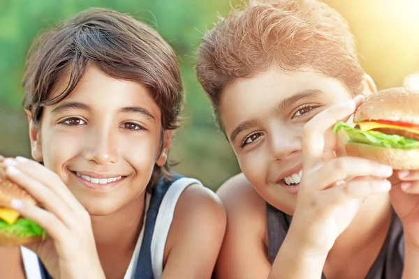 Niños felices comiendo hamburguesas —  Fotos de Stock