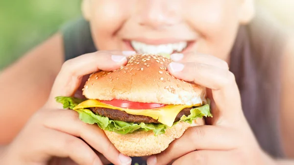 ハンバーガーを食べて幸せな十代の少年 — ストック写真