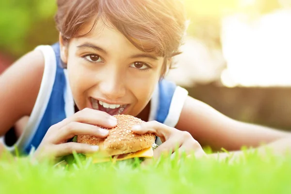 ハンバーガーを食べて幸せな少年 — ストック写真