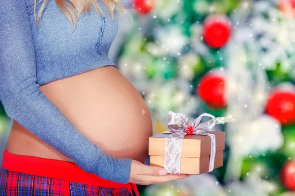Беременная женщина с рождественским подарком — стоковое фото