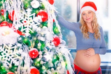 Pregnant woman adorns Christmas tree clipart