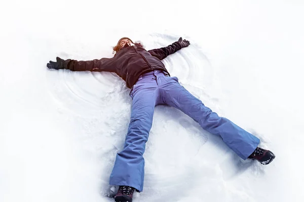 Ung kvinna att göra snöängel — Stockfoto
