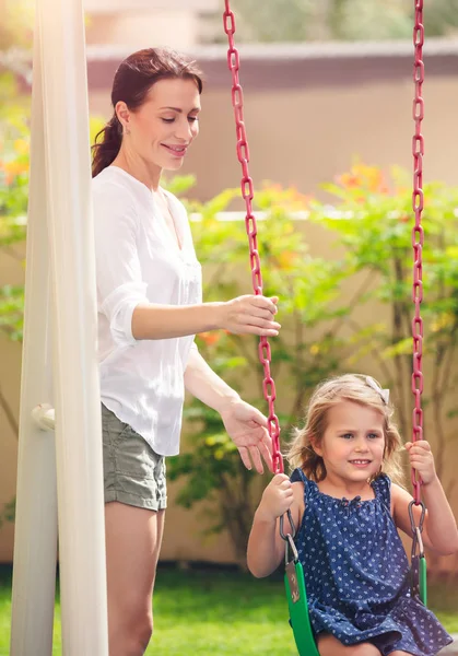 Mamma rocce sua figlia su un swing — Foto Stock