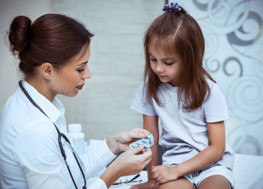 Çocuk doktoru küçük bir kıza reçete yazıyor. Çocuk için tedavi gören genç bir kadın doktor. Virüs tedavisi, sağlık danışmanı.