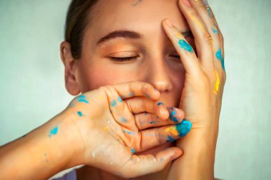 Yaratıcılığın ve sanatın kavramsal fotoğrafı, rüya gibi bir yüzü, boya lekeli parmakları, farkındalığı ve yeni bir fikri görselleştiren güzel bir kadın.