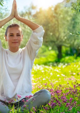 Güzel bir kadın dışarıda yoga egzersizi yapıyor, güzel bir kadın Lotus 'ta poz veriyor güzel bir bahar bahçesinde meditasyon yapıyor, sağlıklı bir yaşam tarzı, rahatlama ve sağIık kavramı.
