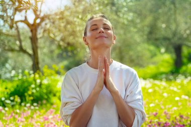 Gözleri kapalı, taze bir bahçede meditasyon yapan neşeli bir kadının portresi. Aklın, bedenin ve ruhun birliği. Sakinlik ve huzur kavramı