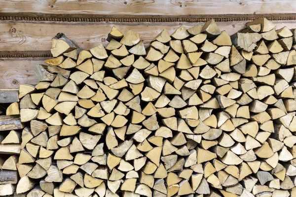 Palivové dřevo skládaný na zdi domu — Stock fotografie