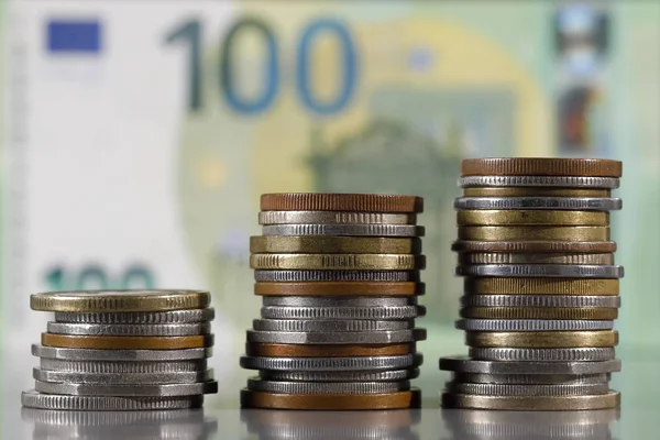 Três pilhas de várias moedas com uma nota de euro — Fotografia de Stock