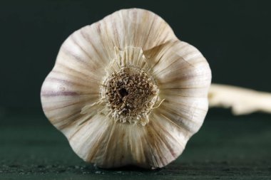 Bir sarımsak koyu yeşil ahşap bir yüzeyde yatıyor..