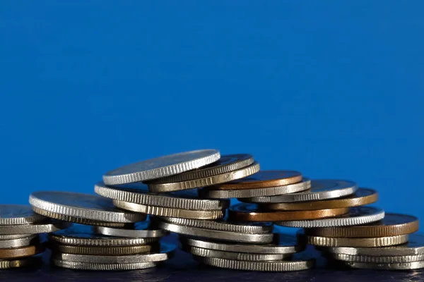 青の背景には様々な硬貨が描かれている これらのコインが置かれている表面は濃い青です — ストック写真
