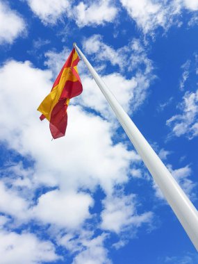 Bir direk gökyüzü ve bulutlar ile İspanya bayrağı
