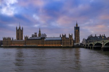 Westminster Sarayı ve Big Ben, Londra 'da gün batımında Thames nehrinde görülen restorasyon için iskeleyle kaplıydı.