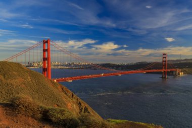 Golden Gate köprüsünün manzarası Marin Burunları ve San Francisco silueti renkli günbatımında, California