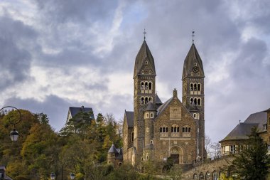 Stone neo romanesk Azizler Katolik Kilisesi Clervaux Lüksemburg 'da Damien' la birlikte sonbaharda bir ormanla çevrili.