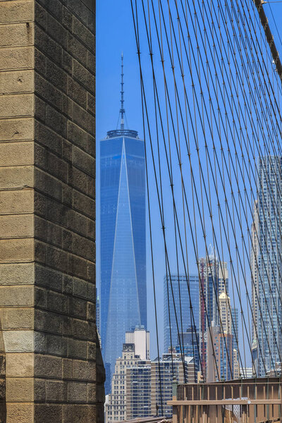 Famous skyline of downtown New York and Lower Manhattan with World Trade Center in New York City, USA seen through the cables of the Brooklyn Bridge