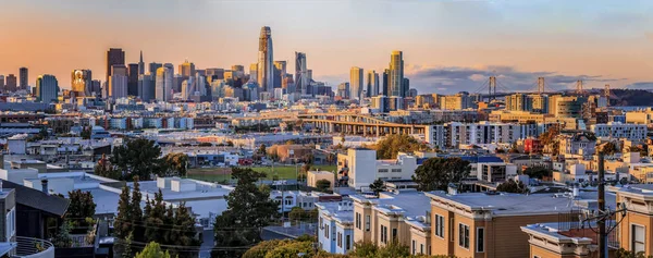 Gün batımında San Francisco gökyüzü manzarası. Renkli bulutlar, Bay Bridge ve şehir merkezindeki finans bölgeleri.