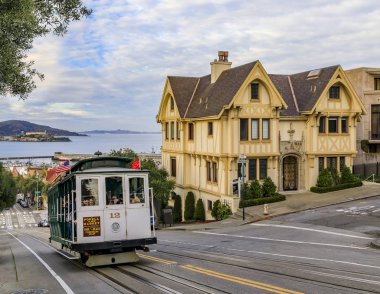 Hyde Caddesi 'nin tepesindeki ikonik teleferik vagonunda turistler, körfeze ve Alcatraz hapishanesine bakıyorlar, San Francisco, Usa
