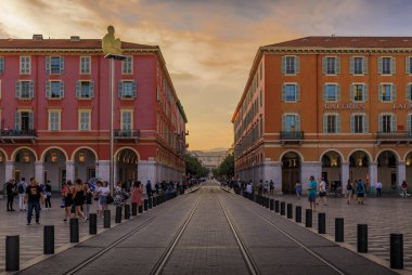 Nice, France - June 2, 2019: Tourists visit Place Massena, major commercial and cultural landmark in Nice at sunset golden hour
