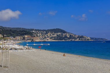 Nice, France - May 23, 2019: People relaxing on the beach near famous Promenade des Anglais with the Mediterranean Sea and coastline in the background