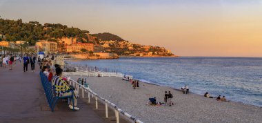 İnsanlar Fransa 'nın Nice kentinde, Akdeniz' in arka planında gezinti güvertesinde dinlenirken,