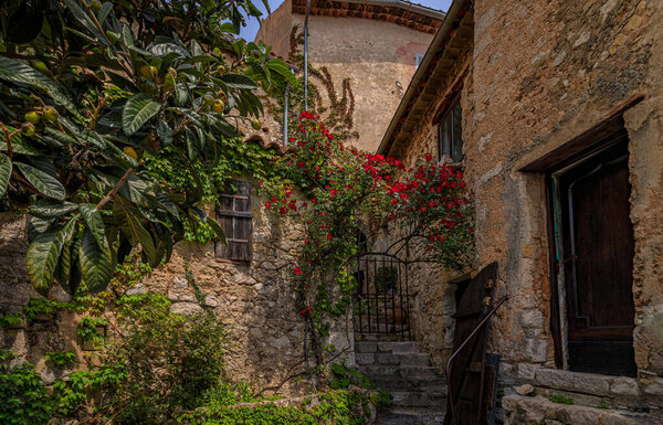 Stone exterior of old buildings with flowers on the streets of Eze Village, picturesque medieval city in South of France along the Mediterranean Sea