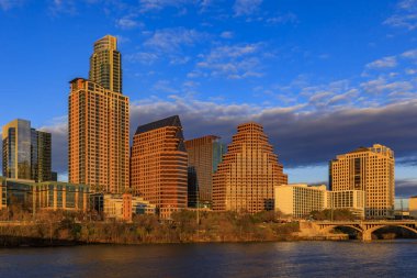 Günbatımını yansıtan şehir merkezindeki gökdelenler Lady Bird Gölü ya da Teksas, Austin 'deki Colorado Nehri üzerindeki Town Lake boyunca görülen altın saat ışığıdır.