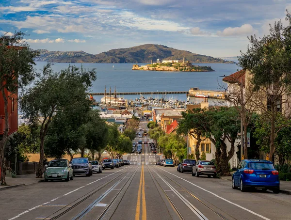 米国カリフォルニア州サンフランシスコを背景に有名なアルカトラズ刑務所島とハイドストリートの上に象徴的なケーブルカートラック — ストック写真
