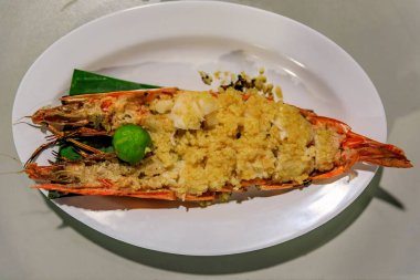 Singapur 'da bir tezgahta servis edilen tabakta kızarmış sarımsak ve limonla kızartılmış büyük karides veya kaplan karidesi.