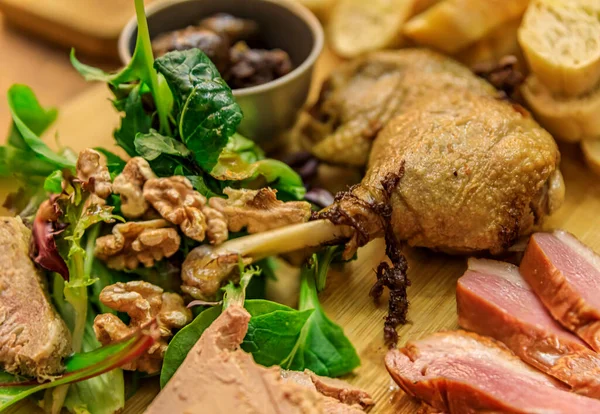 Prato gourmet com pato, foie gras, confit de pato e peito de pato em uma tábua de corte de madeira em um restaurante — Fotografia de Stock