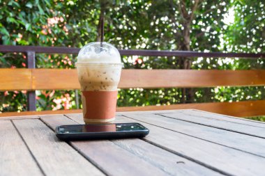 Buzlu kahve ve ahşap masa üstünde smartphone