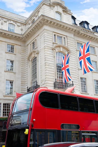 London buss och brittiska flaggor i Piccadilly Circus — Stockfoto