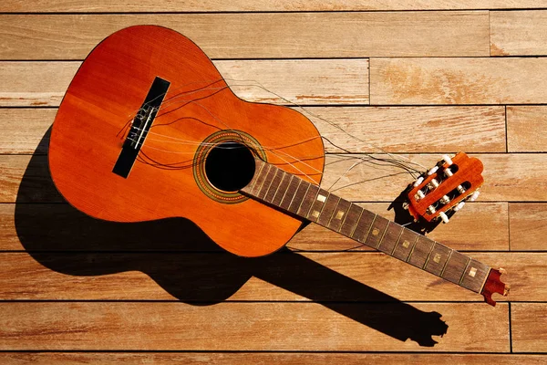 Сломанная испанская гитара на деревянной палубе — стоковое фото