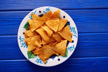 Nachos chips on mexican plate over blue clipart