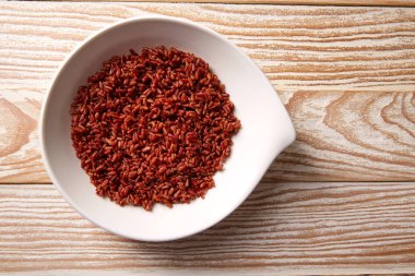 Ahşap üzerinde beyaz bir tabak içinde kırmızı yabani pirinç