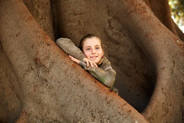 Ξανθό παιδί κορίτσι χαμογελά όπλων στο μεγάλο δέντρου Ficus — Φωτογραφία Αρχείου