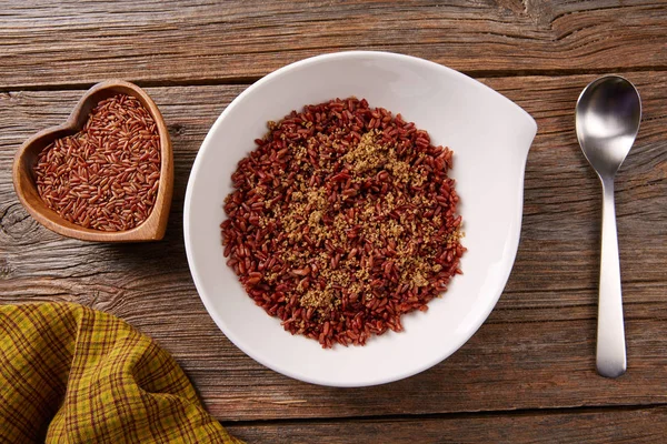 Arroz selvagem vermelho em uma placa branca sobre a madeira — Fotografia de Stock