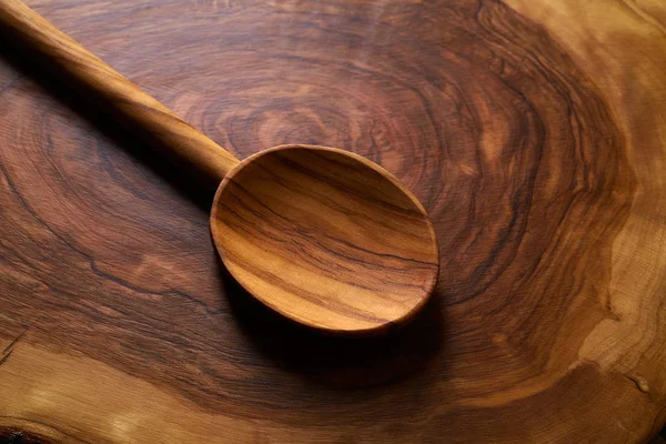 Cuchara de madera de olivo sobre tabla de cortar de madera —  Fotos de Stock