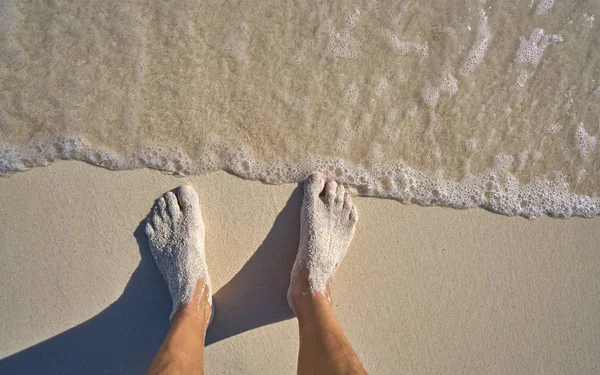Karibská turistické mužské nohy na bílém písku pobřeží — Stock fotografie