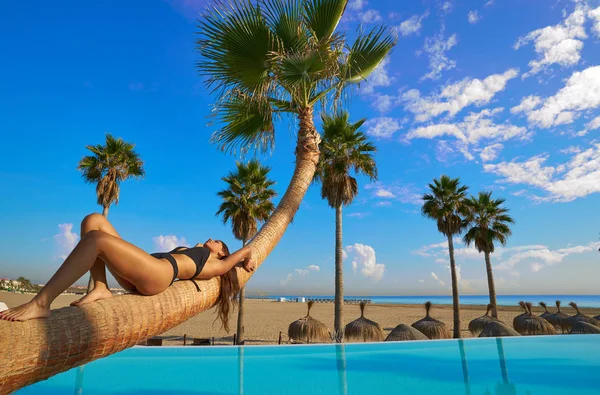 Vrouw liggend op zwembad gebogen palm boomstam — Stockfoto