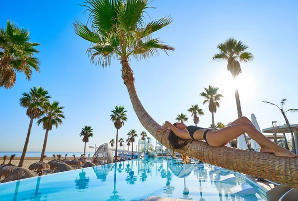 Vrouw liggend op zwembad gebogen palm boomstam — Stockfoto