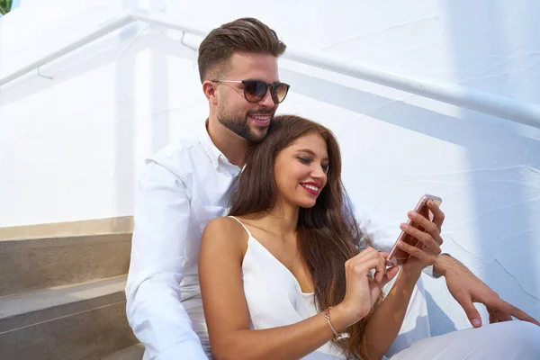 Young couple reading smarphone in a stairway — Stock Photo, Image