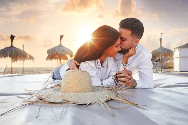 Couple young on beach lounge sunset — Stock Photo, Image