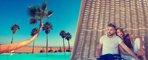 Couple in beach parasol at tropical beach — Stock Photo, Image