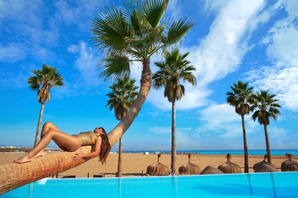 Woman lying on pool bent palm tree trunk — Stock Photo, Image