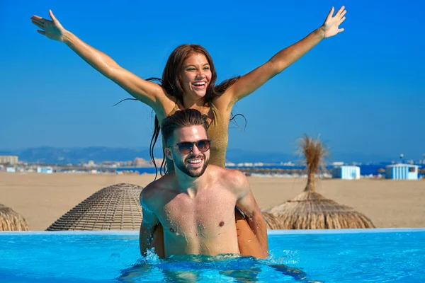 Tourist couple piggyback in infinity pool — Stock Photo, Image