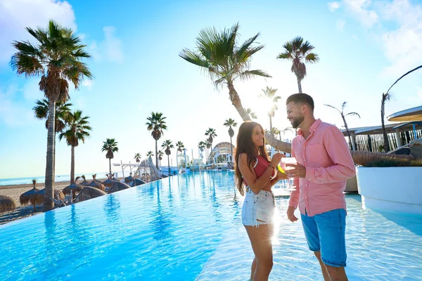 Joven pareja bebiendo cóctel en piscina resort —  Fotos de Stock