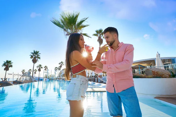 Joven pareja bebiendo cóctel en piscina resort —  Fotos de Stock
