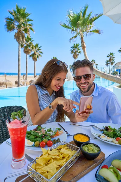 Unga par med smartphone i poolrestaurangen — Stockfoto