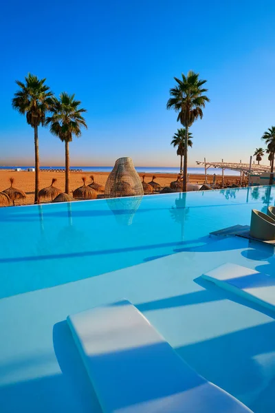 Resort infinity pool in a beach with palm trees — Stock Photo, Image